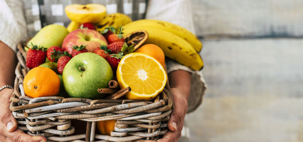 Midsection of woman holding fruits in container