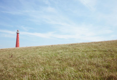 Lighthouse on field against sky