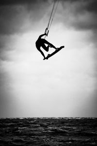 Low angle view of man swinging in sea against sky