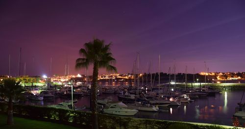Boats moored at harbor against sky at night