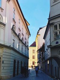 Rear view of people walking on street amidst buildings in city