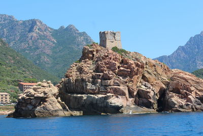 Distant view of castle on rock formation by sea