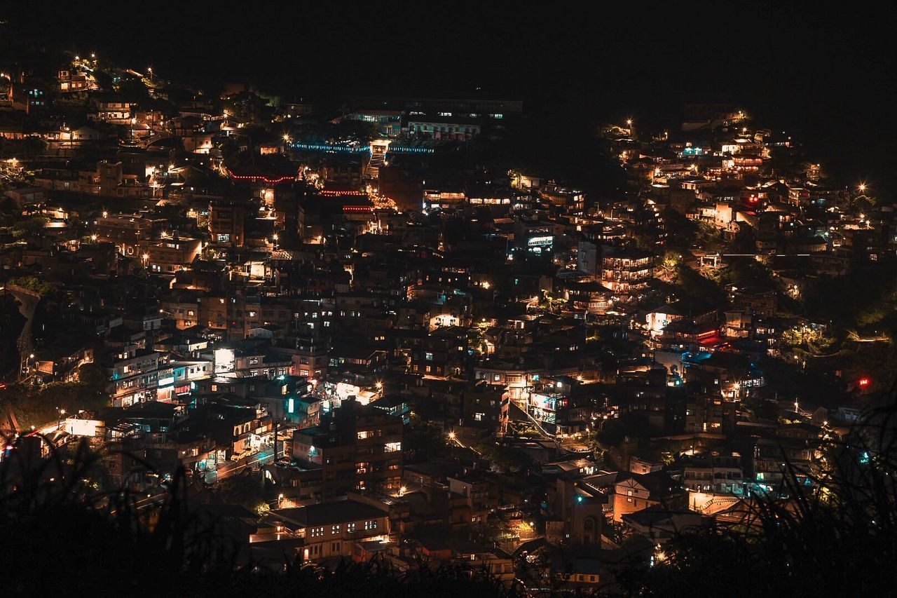 HIGH ANGLE VIEW OF ILLUMINATED MODERN BUILDINGS IN CITY AT NIGHT