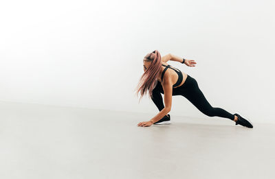 Full length of woman dancing against white background