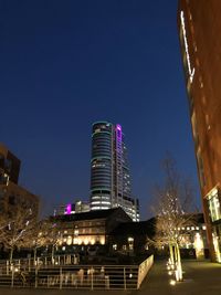 Low angle view of illuminated buildings against clear sky at night