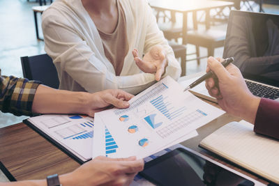 Colleagues discussing over graph at desk in office