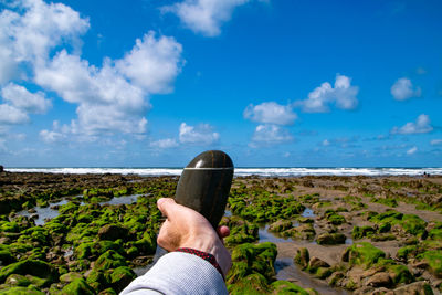 Low section of person standing on beach against sky
