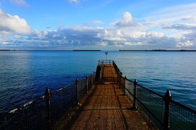 View of pier on calm sea against cloudy sky