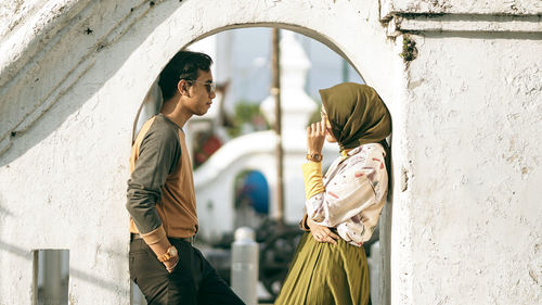 Side view of woman standing against wall