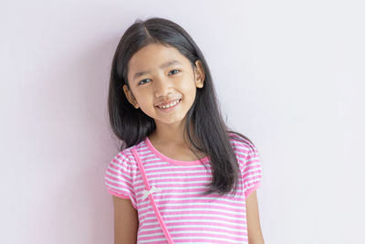 Portrait of a smiling girl standing against white background