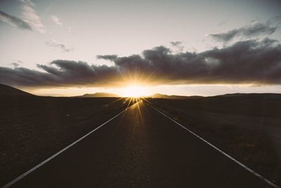 Road passing through landscape during sunset