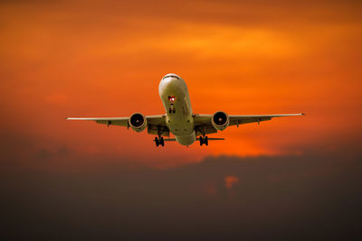 Low angle view of airplane flying against sky during sunset