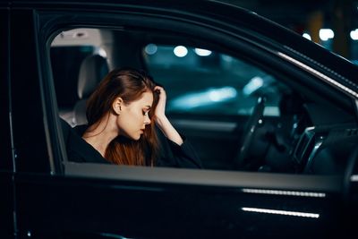 Side view of woman sitting with hand in hair