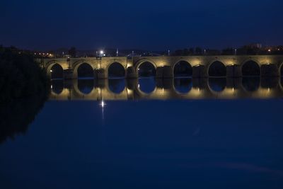 Illuminated bridge against sky at night