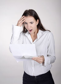 Tensed woman holding document against white background