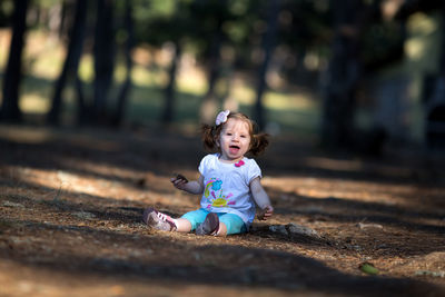 Full length of cheerful girl sitting at park