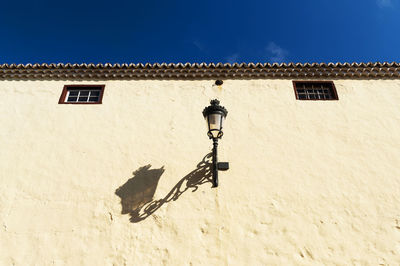 Low angle view of gas light with shadow on building