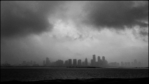 City buildings by sea against sky