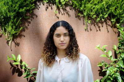 Portrait of young woman standing against wall
