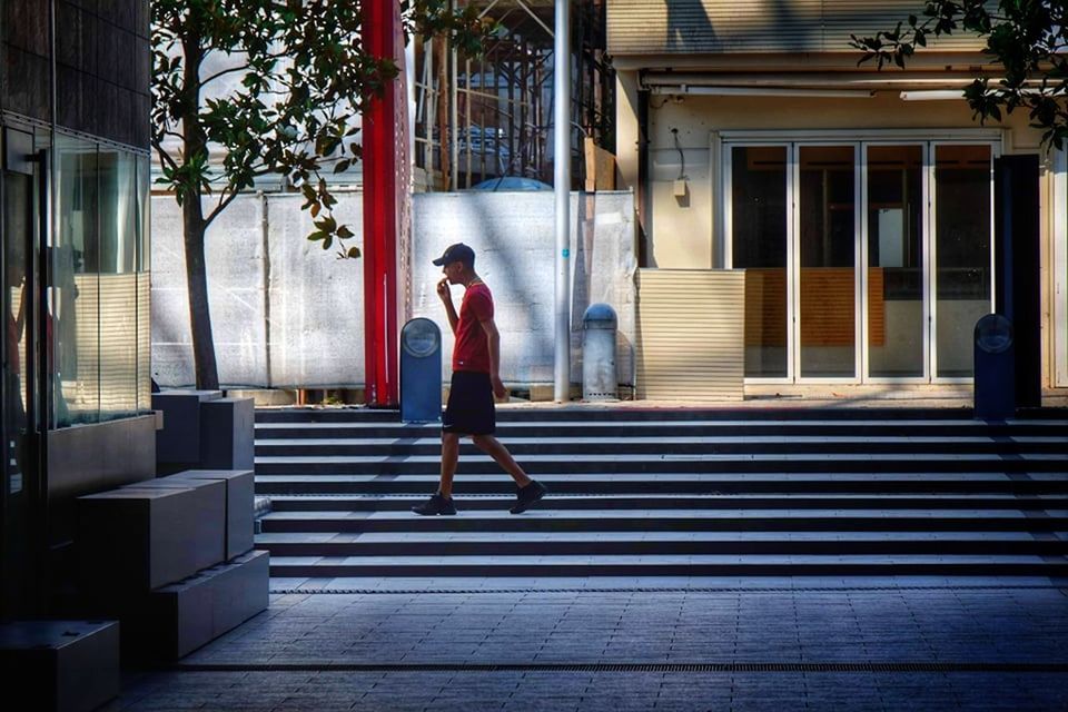 FULL LENGTH REAR VIEW OF WOMAN WALKING ON STREET AGAINST BUILDING