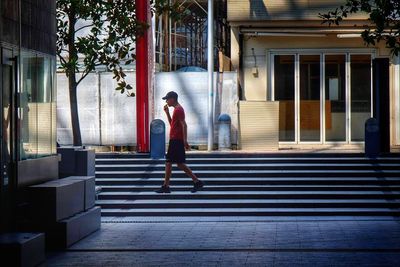 Full length rear view of woman walking on street in city