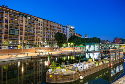 Bridge over river against buildings in city against clear blue sky