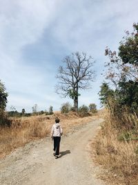 Rear view of man walking on road against sky