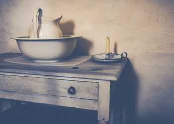 Candle in bowl on table at home