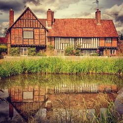 Houses by lake against sky