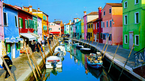 Boats moored in canal amidst buildings in city