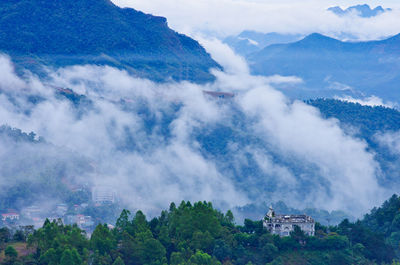 Aerial view of trees and buildings against cloudy sky