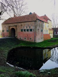 House by lake against sky