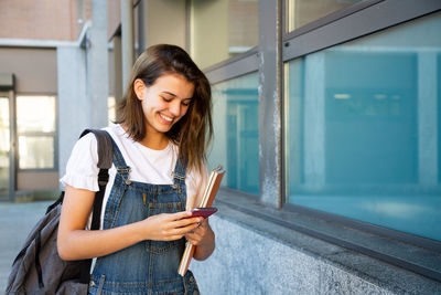 Portrait of smiling woman standing on mobile phone