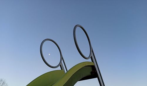 Low angle view of metal against clear blue sky