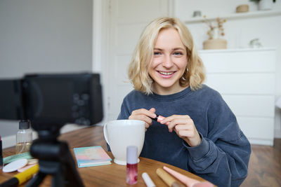 Portrait of smiling young woman using mobile phone at home