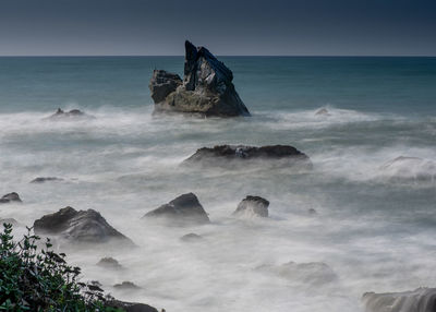 Scenic view of rocks in sea against sky