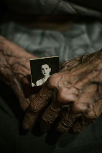 From above anonymous elderly person holding aged photo at home person