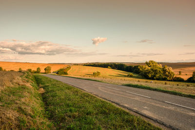 Road amidst field against sky