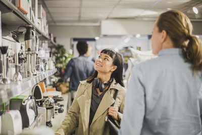 Young customer looking at appliances while standing by mature female owner in store