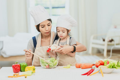 Mother and daughter with ice cream in kitchen