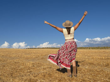 Rear view of woman standing on field against sky