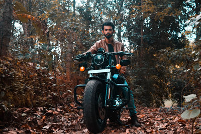 Portrait of man with umbrella on leaves in forest