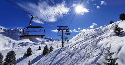 Ski lift over snowcapped mountains against sky