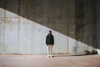 Full length of young man standing against wall