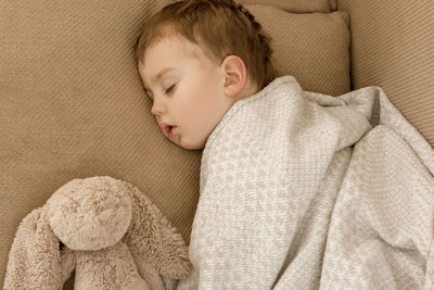 Little, cute caucasian boy sleeping on couch at home. child taking day nap. kid resting, relaxing 