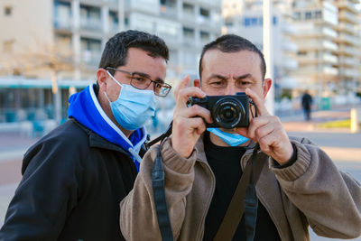 Two men taking pictures with a professional reflex camera.