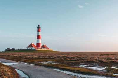 Lighthouse by sea against sky