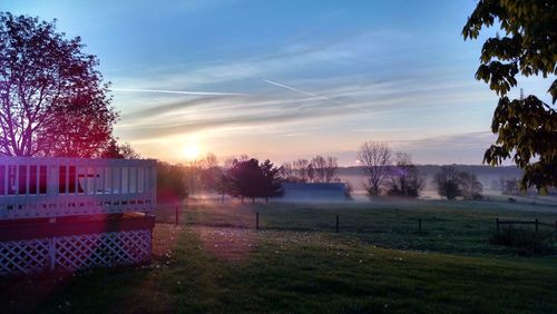 Scenic view of grassy field against sky at sunset