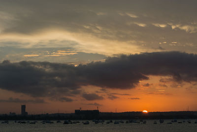 Scenic view of sea against dramatic sky during sunset