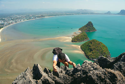 High angle view of man climbing on mountain against sea